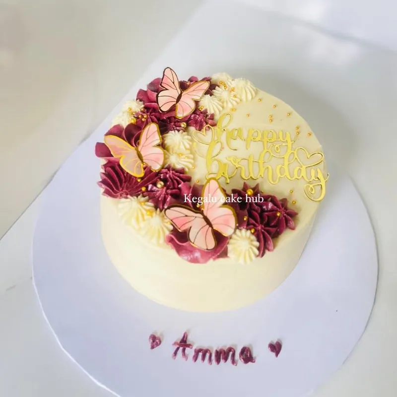 Cream birthday cake with blush butterflies and hand-piped flowers