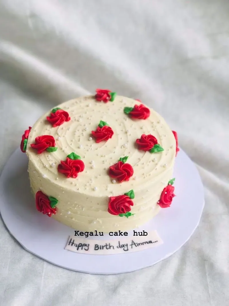 Cream cake decorated with red piped buttercream roses and pearl sprinkles