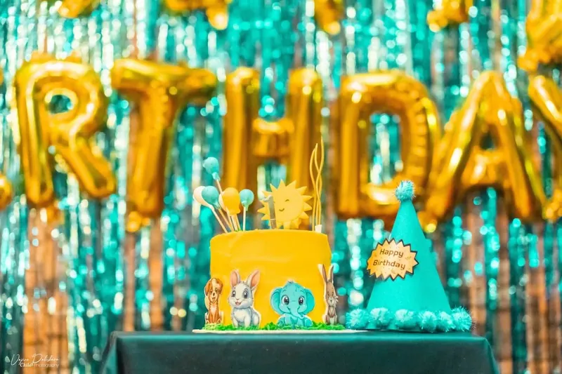 Bright yellow first birthday cake with safari animal cut-outs and a birthday party backdrop