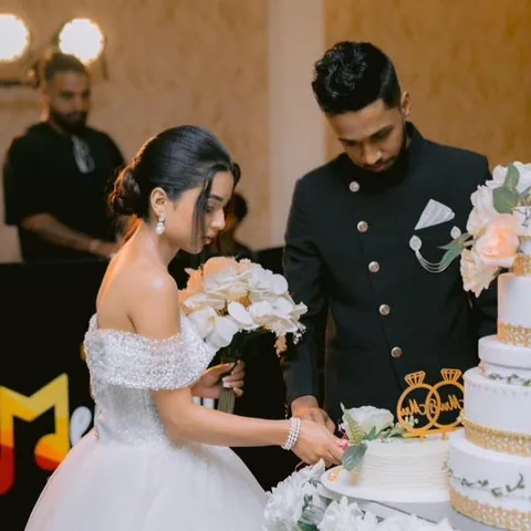 Bride and groom cutting a white wedding cake surrounded by flowers